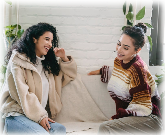 Two women sittting on a couch laughing and talking