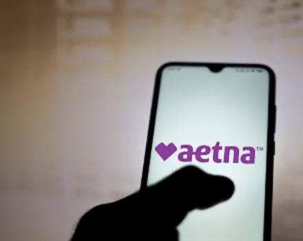 Smartphone displaying Aetna insurance company logo on screen, representing insurance coverage and healthcare benefits for mental health services