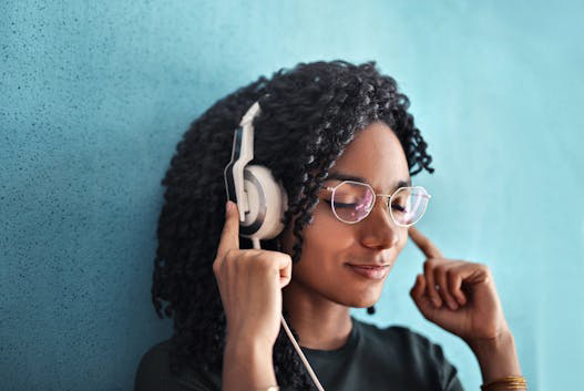 Lady with eyes closed and her headphones on relaxing.