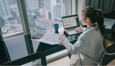 Woman working at laptop in office setting by window, representing someone taking an online mental health assessment