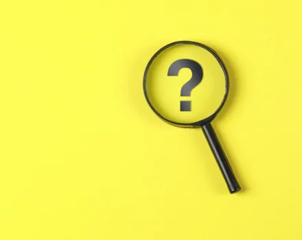 Magnifying glass with question mark inside on bright yellow background, symbolizing the search for answers and information about mental health topics