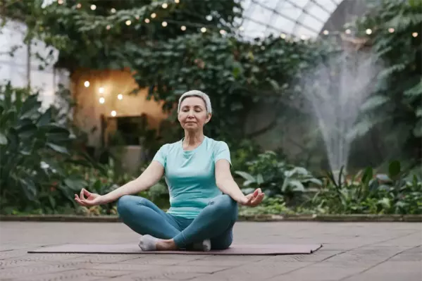 Lady sitting on a yoga mat with her legs crossed meditating