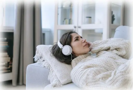 A lady laying down on her couch listening to her music as she takes her first session with Almadelic.
